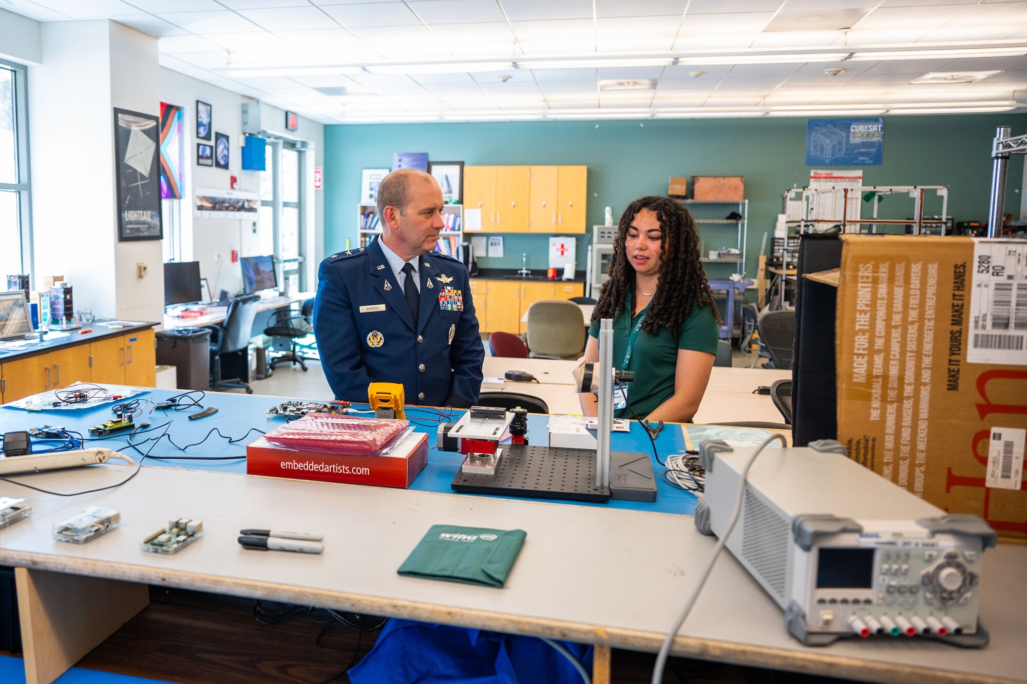 U.S. Space Force Maj. Gen. Douglas A. Schiess, Combined Force Space Component Command commander, left, and Kayla Del Rosario, California Polytechnic State University mechanical engineer student, discuss current and future projects of the Cal Poly CubeSat Laboratory at California Polytechnic State University in San Luis Obispo, Calif., April 25, 2023. The Cal Poly CubeSat Laboratory is part of PolySat, a student-run, multidisciplinary independent research lab at the university which partnered with Vandenberg through a Cooperative Research and Development Agreement (CRADA) in 2019, the first of its kind between the base and an academic institution. A CRADA is a no-cost collaboration that enables the transfer and exchange of technology and professional expertise. (U.S. Space Force photo by Tech. Sgt. Luke Kitterman)