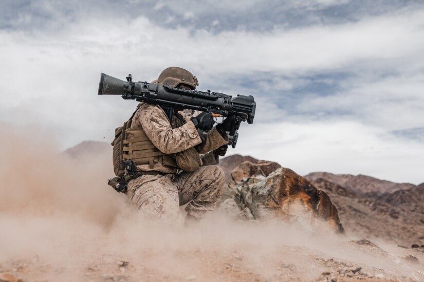 A Marine crouches with a missile launcher on the shoulder in a dusty area.