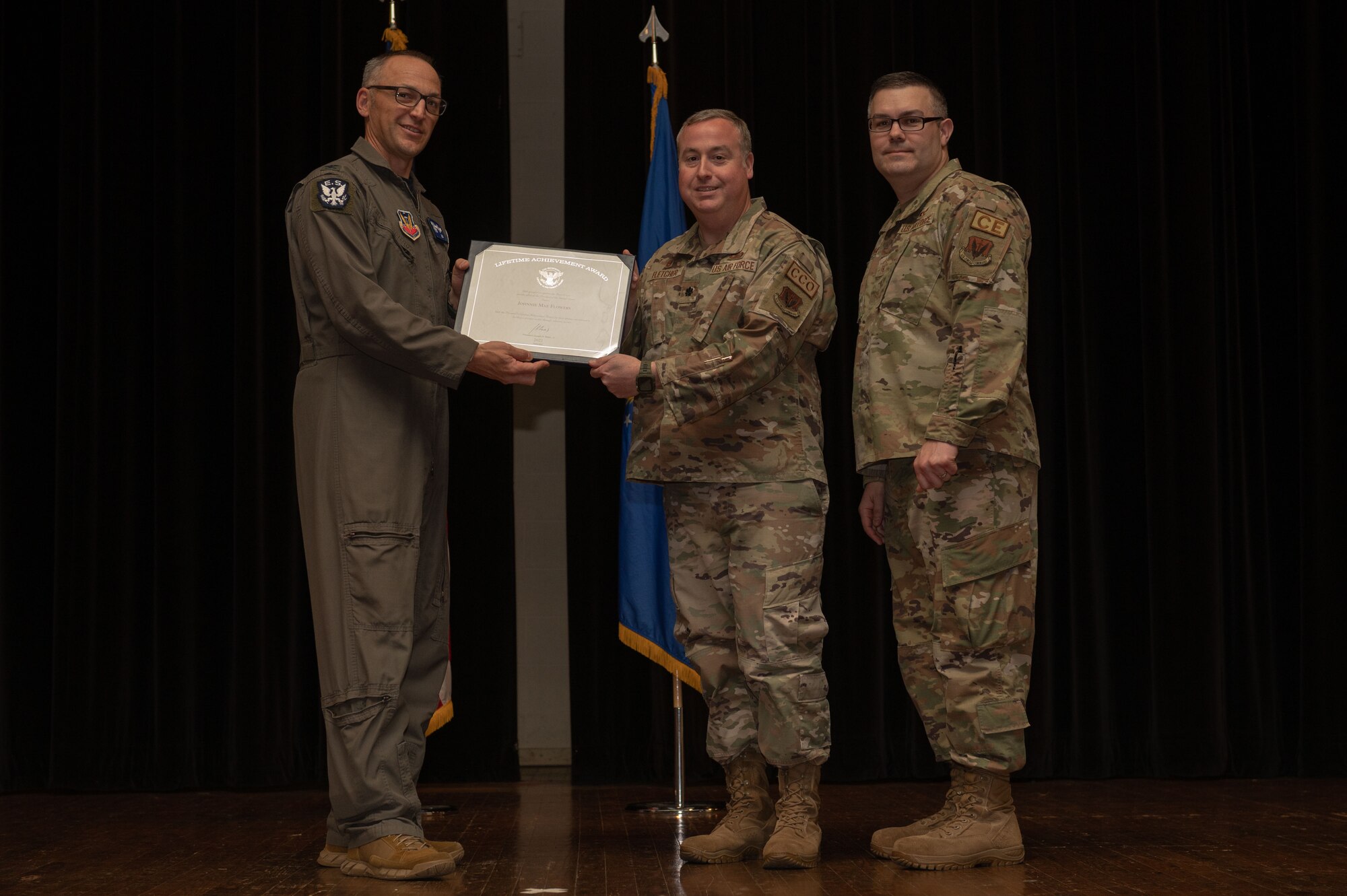 Col. Steven Bofferding, left, 4th Fighter Wing vice commander, Chief Master Sgt. Kyle O’Hara, right, 4th Civil Engineer Squadron command chief, present the Lifetime Achievement Award to Lt Col. Steven Fletcher, center, 414th Maintenance Squadron commander, who accepts the award for Johnnie Mae Flowers, during a volunteer appreciation ceremony at Seymour Johnson Air Force Base, North Carolina, April 21, 2023. The Lifetime Achievement Award is presented to those who have accumulated over 4,000 hours of volunteer hours. (U.S. Air Force photo by Airman 1st Class Rebecca Sirimarco-Lang)