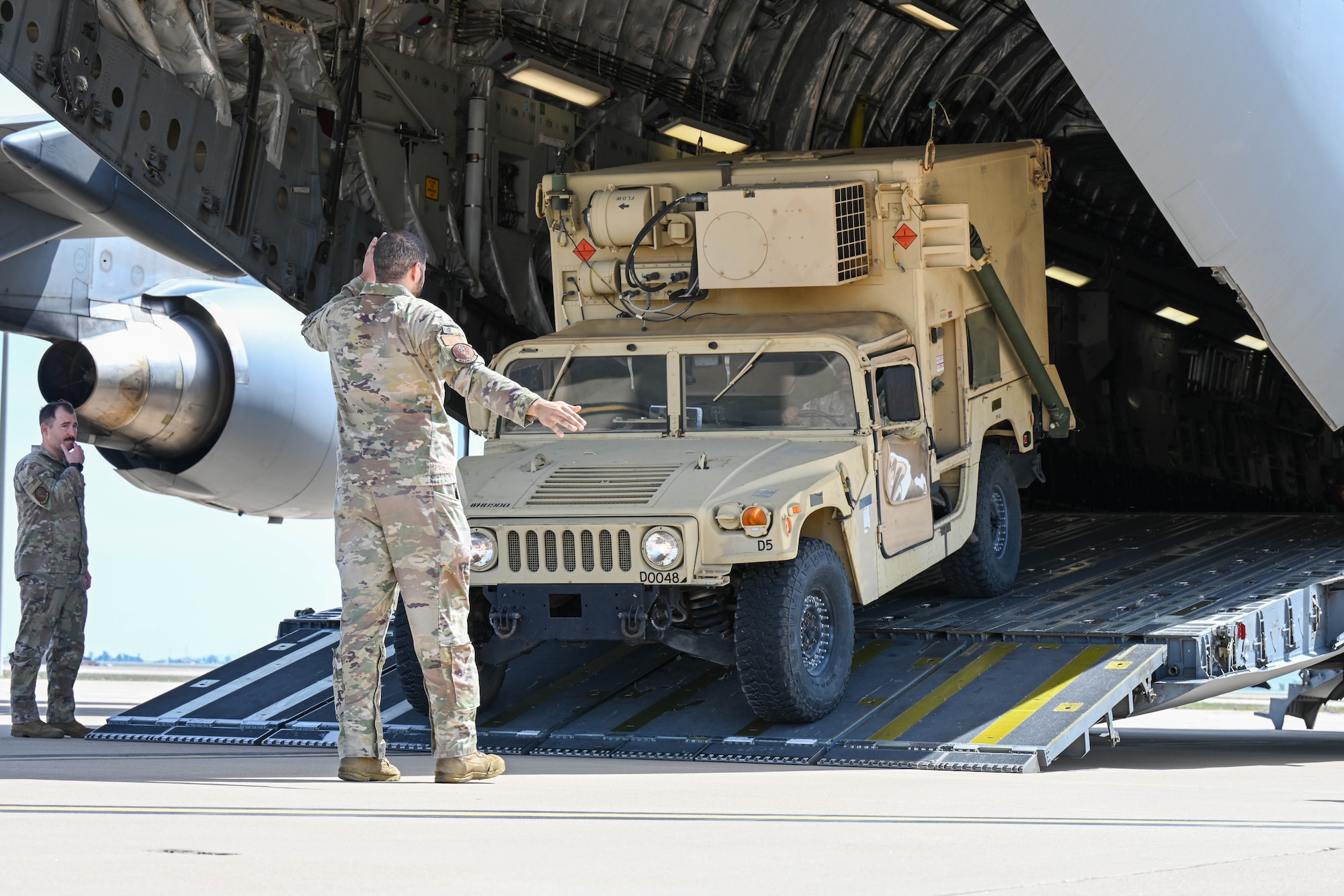 U.S. Air Force Staff Sgt. Asa Abdallah, 58th Airlift Squadron (AS) loadmaster instructor, signals to U.S. Army Spc. Toyvin Brand, 31st Air Defense Artillery Brigade advance early warning systems operator, as he drives up a C-17 Globemaster III ramp at Altus Air Force Base, Oklahoma, April 19, 2023. Three loadmaster instructors from the 58th AS helped guide Soldiers as they uploaded vehicles onto the C-17. (U.S. Air Force photo by Senior Airman Trenton Jancze)