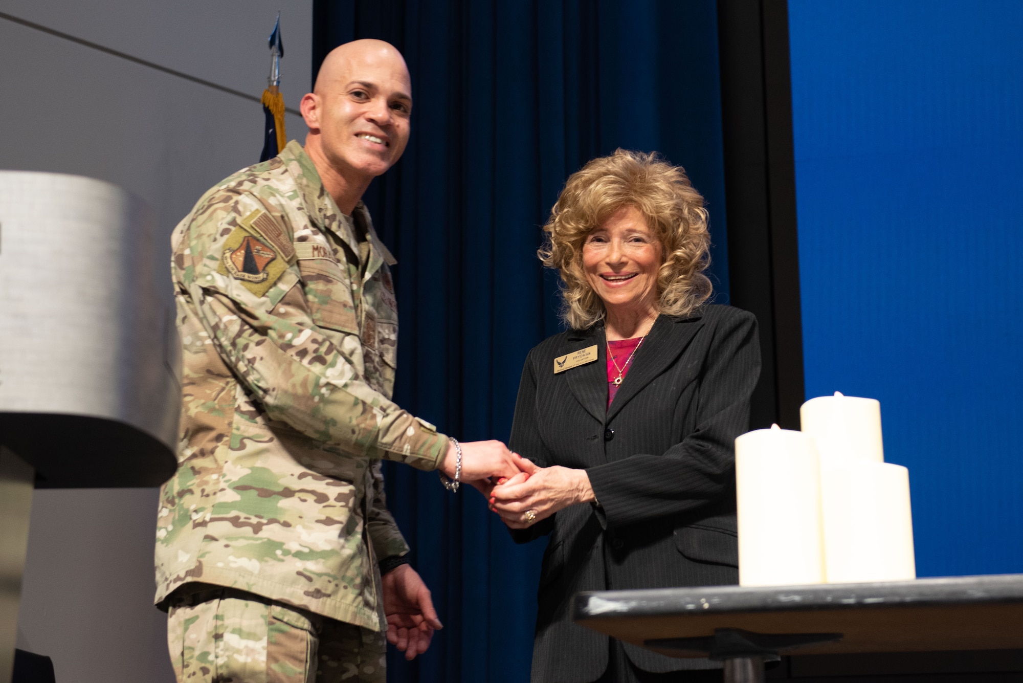 Chief Master Sgt. Lloyd Morales, left, 88th Air Base Wing command chief, awards Dr. Renate Frydman, Holocaust survivor and curator and docent for the Holocaust exhibit at the National Museum of the United States Air Force as well as the director of the Dayton Holocaust Resource Center, with an 88th Air Base Wing coin at Wright-Patterson Air Force Base, Ohio. Wright-Patterson observes Holocaust Remembrance Day every year to honor those six million Jews who were persecuted and murdered by the Nazi Germans during the Holocaust. (U.S. Air Force photo by Darrius Parker)