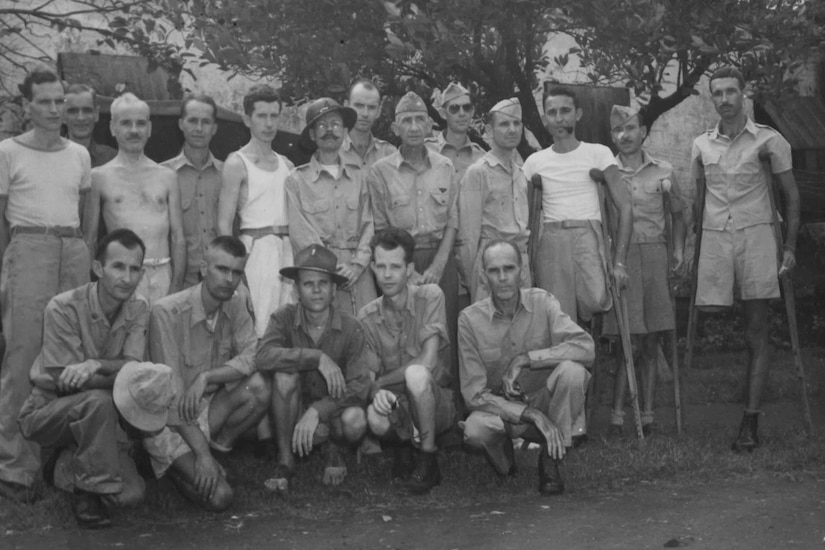 Three rows of men, some of whom are missing limbs, pose for a photo.