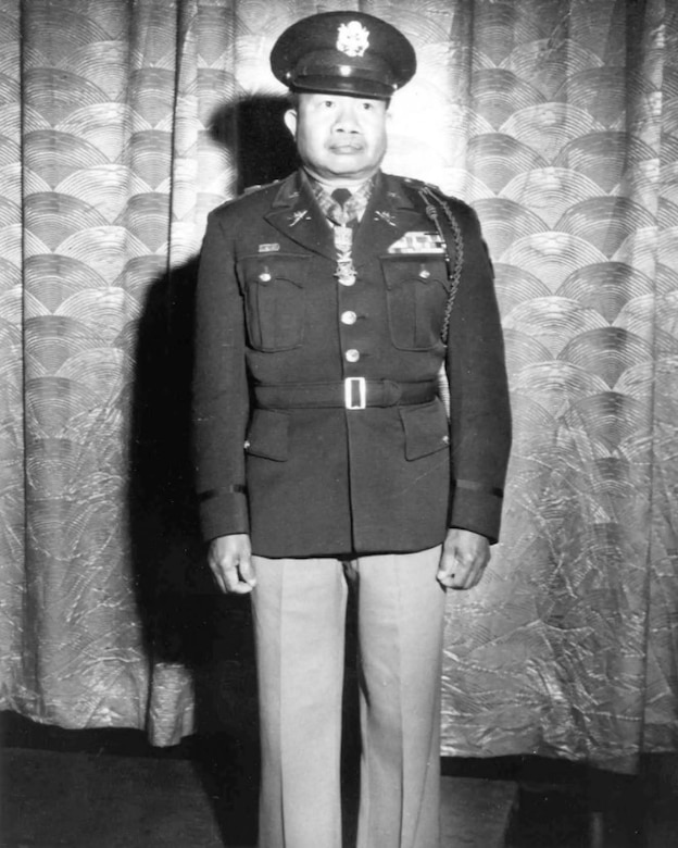 A man in dress uniform stands at attention.