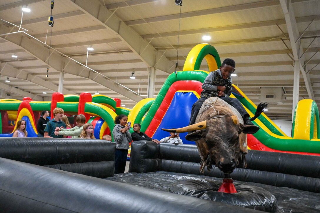 A child rides the mechanical bull during an event hosted by the Altus Chamber of Commerce’s Committee of 100 at the Jackson County Expo Center in Altus, Oklahoma, April 24, 2023.Airmen and families had the opportunity to meet Committee of 100 members, have dinner and enjoy obstacle courses, bounce houses, flight simulators, and a mechanical bull. (U.S. Air Force photo by Airman 1st Class Kari Degraffenreed)