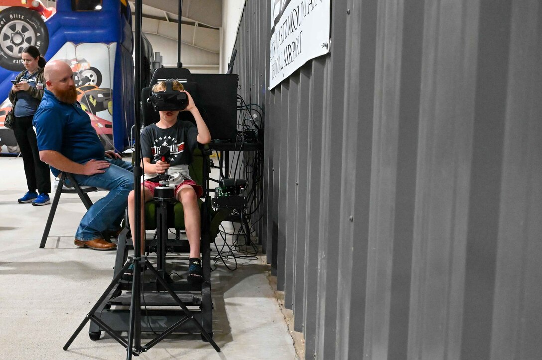 A child plays with the flight simulator at the Altus Chamber of Commerce’s Committee of 100military appreciation dinner in Altus, Oklahoma, April 24, 2023. The Altus/Quartz Mountain Regional Airport provided the simulator for the event. (U.S. Air Force photo by Airman 1st Class Kari Degraffenreed)