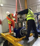 Technical experts from Nigeria's Centre for Energy Research and Training (CERT) stand over the Miniature Neutron Source Reactor (MNSR) and prepare to load the HEU reactor core into an Interim Transfer Cask. (NNSA)