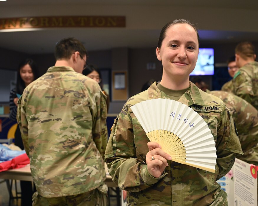 U.S. Army Staff Sgt. Sabrina Heiderscheit, 316th Training Squadron student, holds a paper fan with her name written in Korean at the Angelo State University and Goodfellow Air Force Base Language and Culture Fair in San Angelo, Texas, April 27, 2023. This is the fourth annual GAFB International Language and Culture Fair and the third annual coordination with ASU. (U.S. Air Force photo by Airman 1st Class Zach Heimbuch)