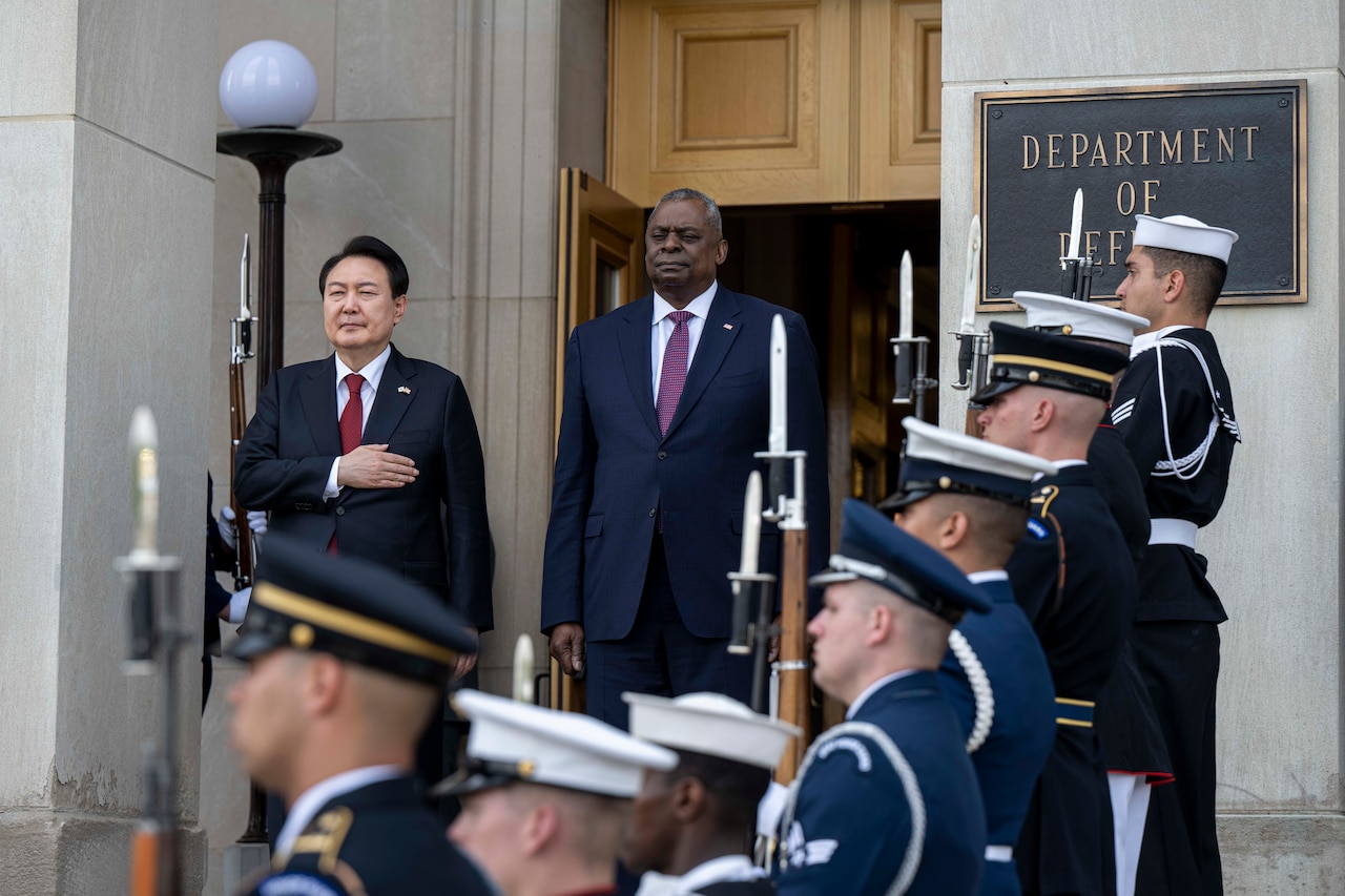 Two men stand next to each other on the steps of the Pentagon during a ceremony.