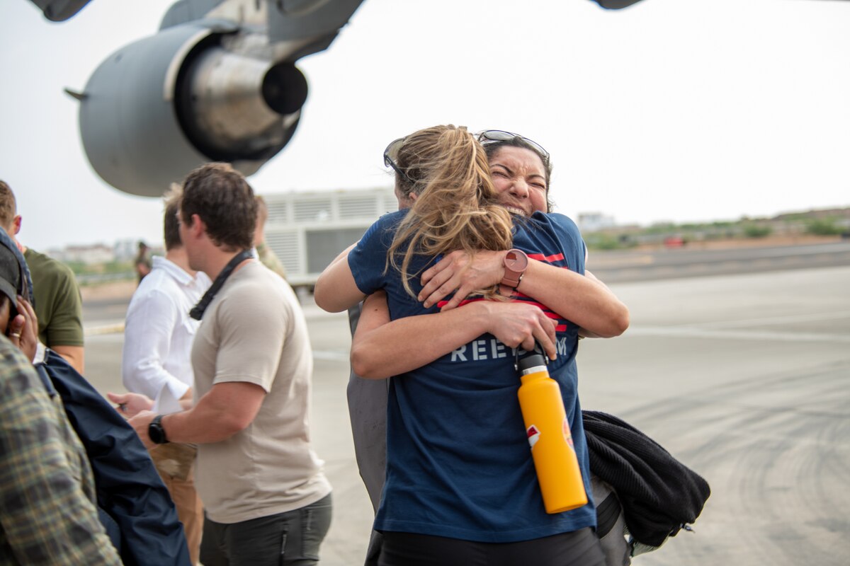 Two women hug on a tarmac.