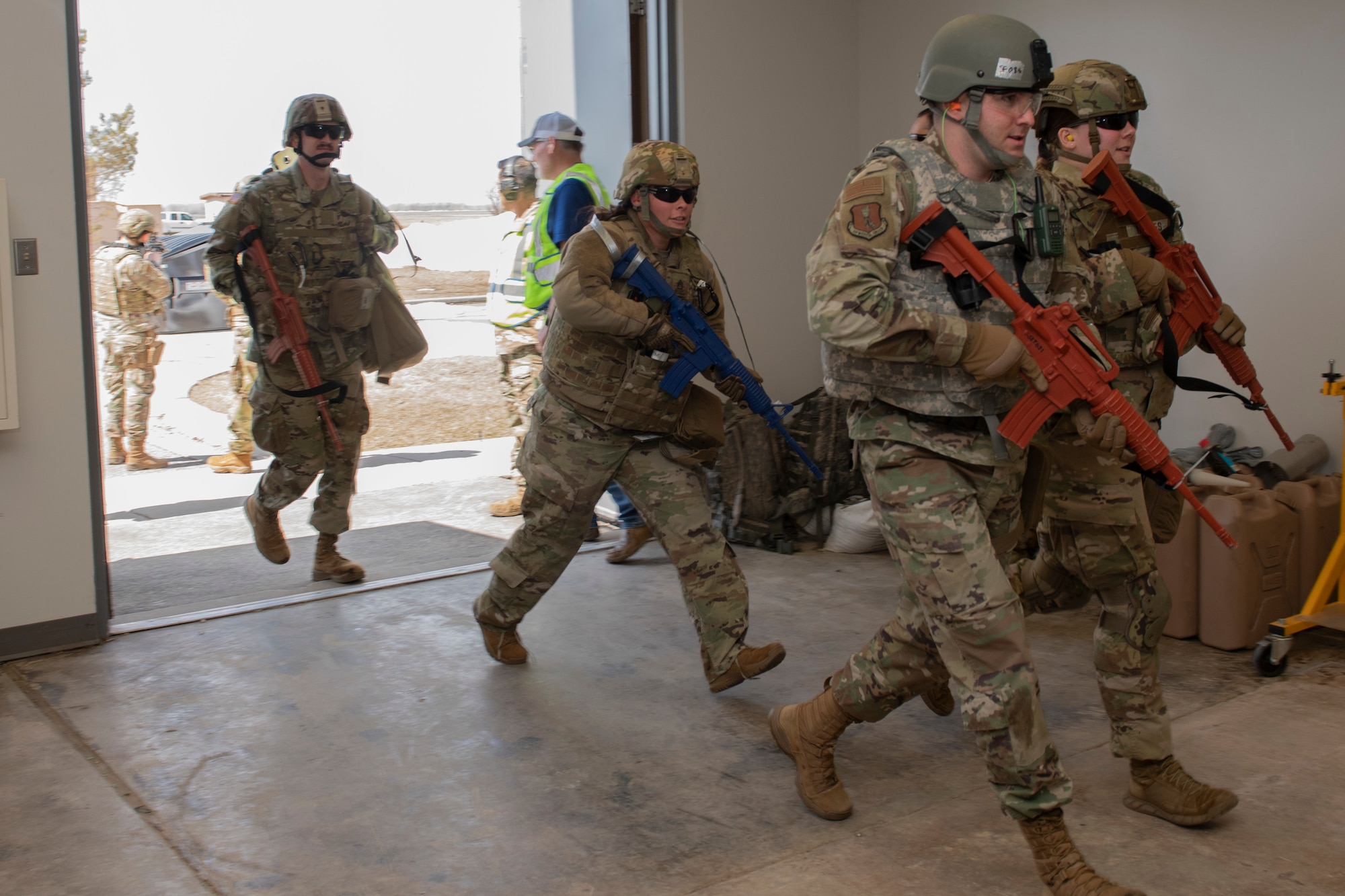 Service members running through an opened door.