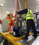 Technical experts from Nigeria's Centre for Energy Research and Training (CERT) stand over the Miniature Neutron Source Reactor (MNSR) and prepare to load the HEU reactor core into an Interim Transfer Cask. (NNSA)