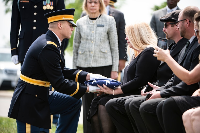 A woman is presented with the American flag during a funeral service.