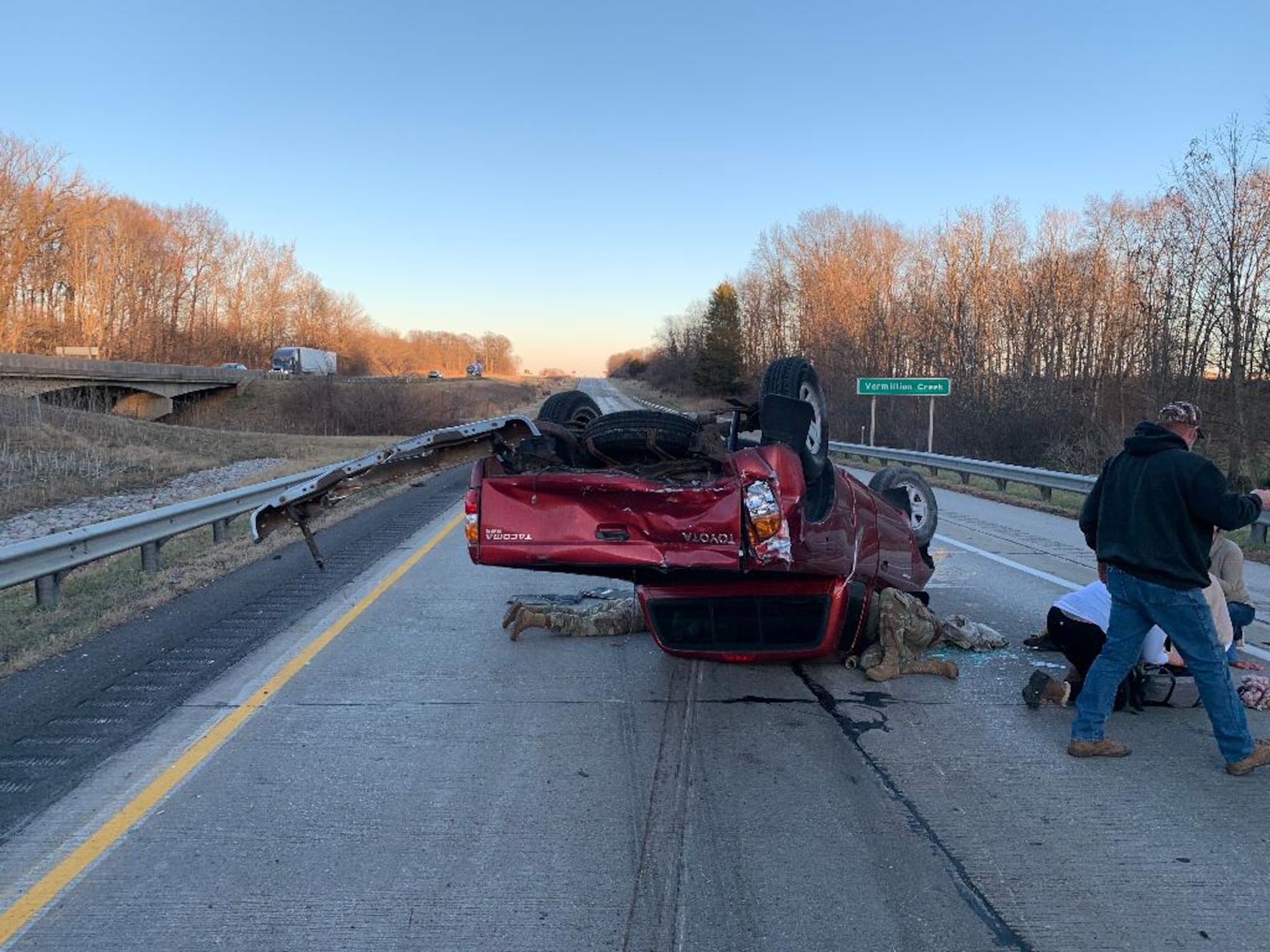 Two members of Indiana’s 19th Chemical, Biological, Radiological, Nuclear, and High-yield Explosives Enhanced Response Force Package medical element help John Carlson and Leslie Legg-Carlson after their vehicle was hit by a car and overturned on I-70 near Cloverdale, Indiana, Dec. 3, 2022.