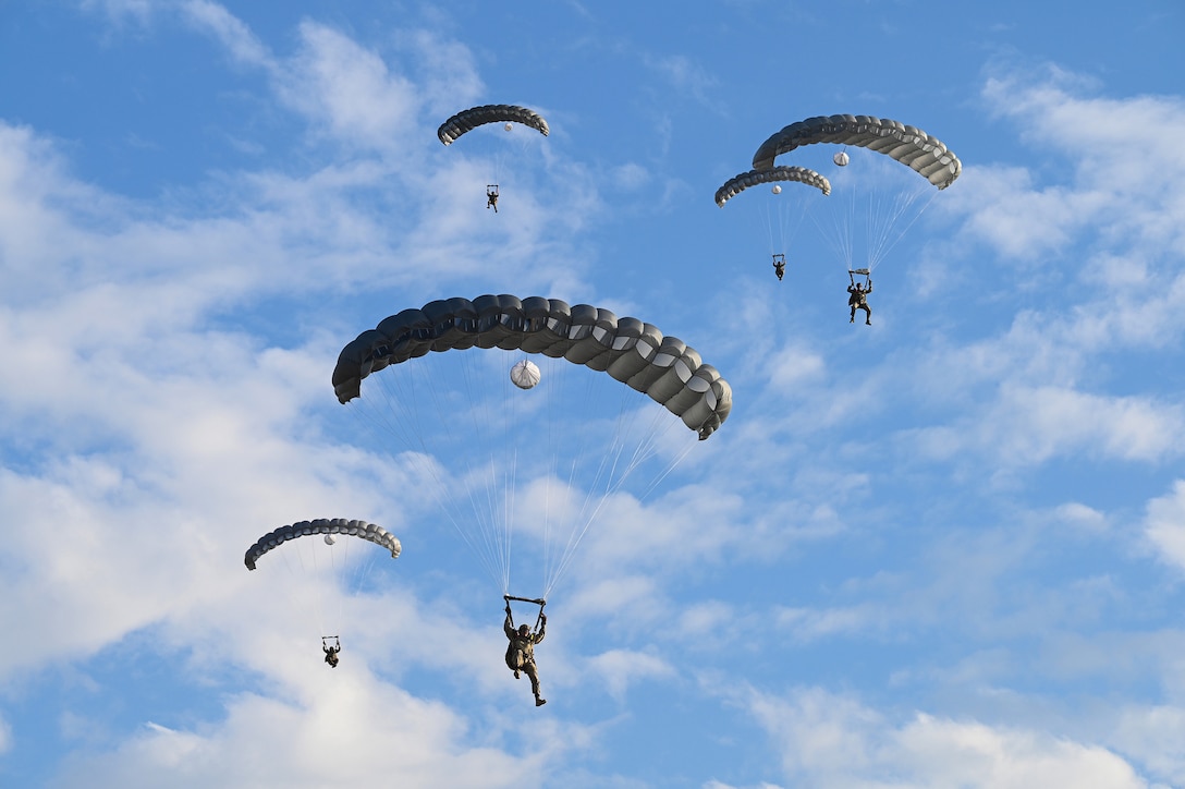 Airmen parachute on a sunny day.