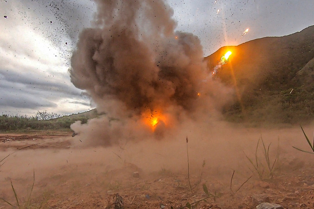 An explosion takes place in a dusty field.
