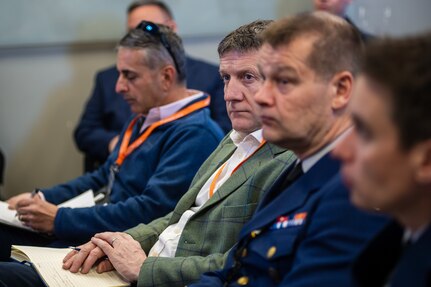 Four men sitting and watching a presentation