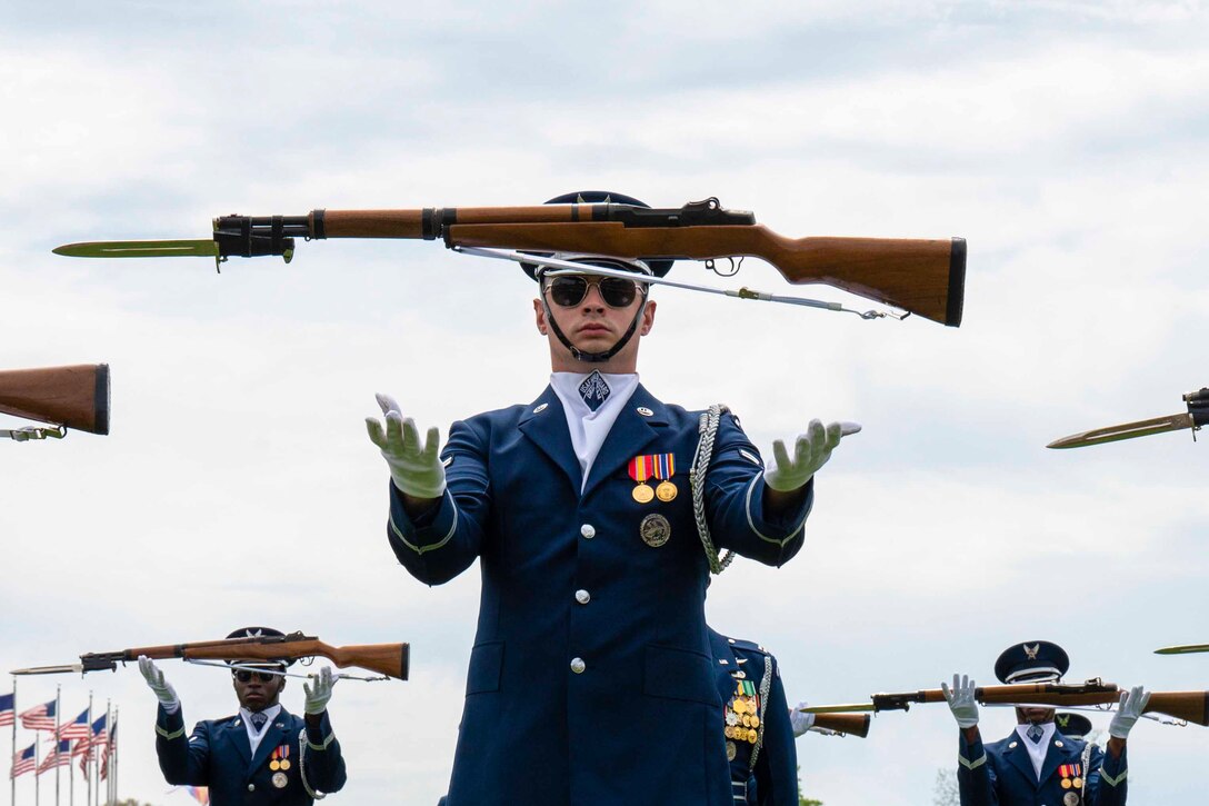 Airmen toss rifles in the air while standing in formation.