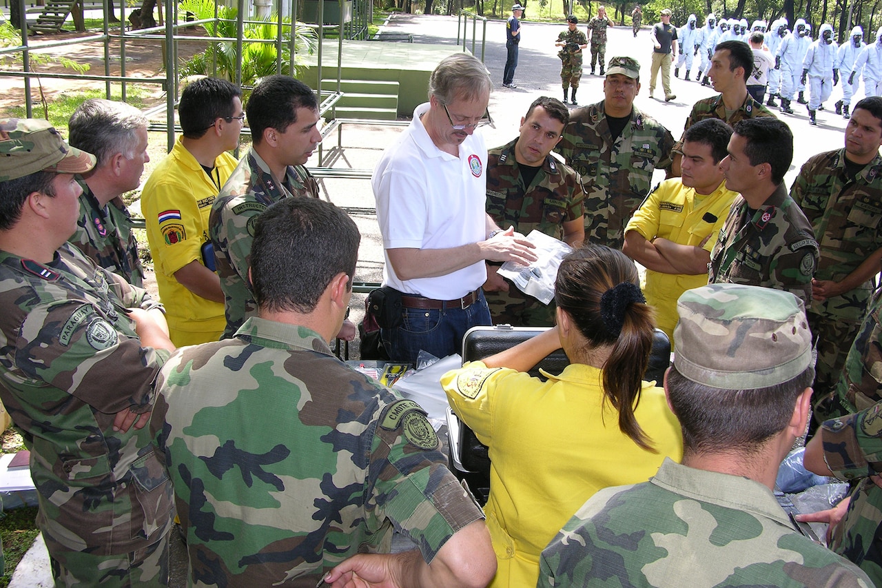 Several people look toward a man holding papers in his hand in the middle of a group.