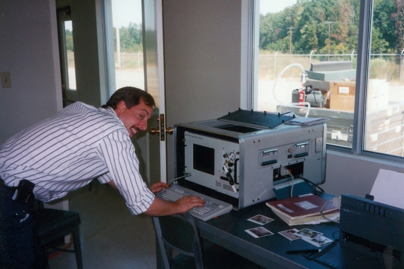 A man leans over a keyboard attached to a large piece of equipment.