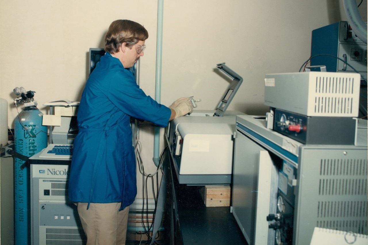 A man looks at small pieces of a larger piece of machinery.