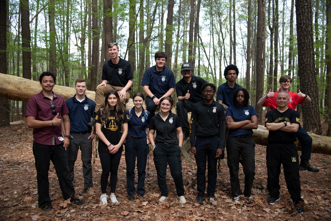 A group of high school students pose together at an obstacle course