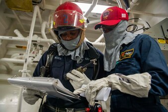 GULF OF OMAN (April 28, 2023) Chief Retail Service Specialist Nicolette Nasario, right, and Damage Controlman 3rd Class Michael Bowden, left, coordinate damage control during a general quarters drill aboard the guided-missile destroyer USS Paul Hamilton (DDG 60), April 28, 2023 in the Gulf of Oman.