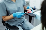 A dentist uses a set of demonstration teeth to show a patient