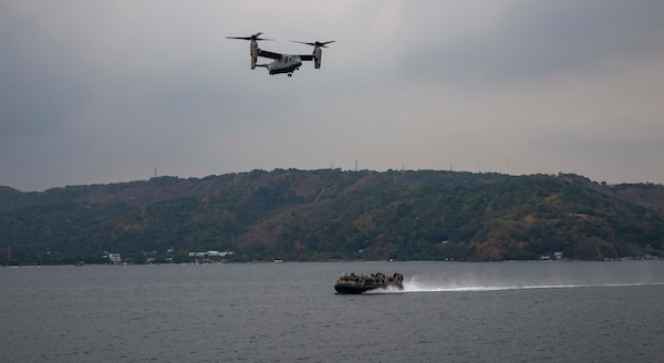 A U.S. Navy landing craft, air cushion, assigned to Assault Craft Unit 5, and a U.S. Marine MV-22 Osprey, assigned to Marine Medium Tiltrotor (VMM) 362 (Rein.), 13th Marine Expeditionary Unit, returns to amphibious assault ship USS Makin Island (LHD 8), during a ship-to-shore operation of Balikatan 23, April 12, 2023 in the Subic Bay Harbor. Balikatan is an annual exercise between the Armed Forces of the Philippines and U.S. military designed to strengthen bilateral interoperability, capabilities, trust, and cooperation built over decades shared experiences. The Makin Island Amphibious Ready Group, comprised of Makin Island and amphibious transport docks USS Anchorage (LPD 23) and USS John P. Murtha (LPD 26), is operating in the U.S. 7th Fleet area of operations with the embarked 13th MEU to enhance interoperability with Allies and partners and serve as a ready-response force to defend peace and maintain stability in the Indo-Pacific region. (U.S. Navy photo by Mass Communication Specialist 3rd Class Eloise A. Johnson)