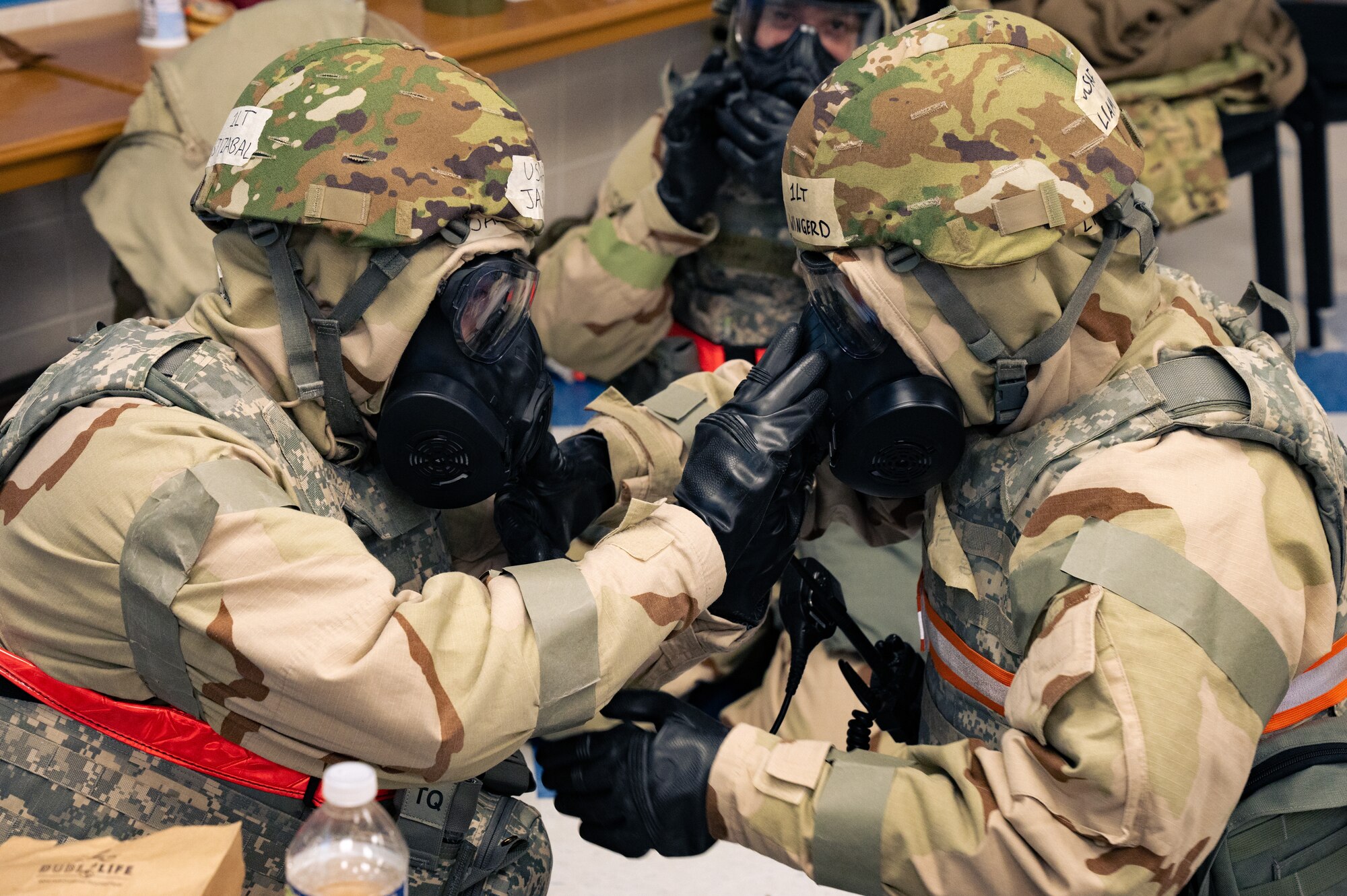 Airmen help each other secure chemical gear.