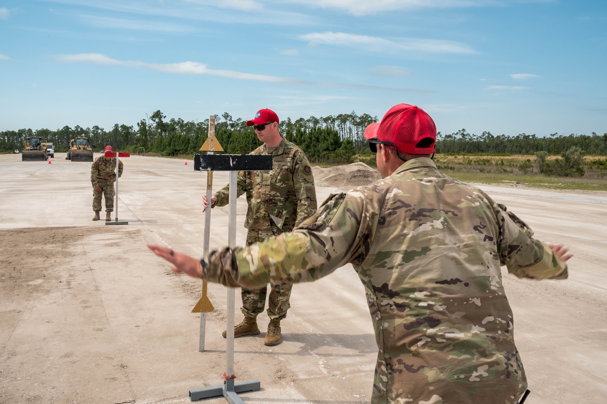 Evaluators with the 801st RED HORSE Training Squadron evaluate an airfield damage crater repair attempt by competitors.