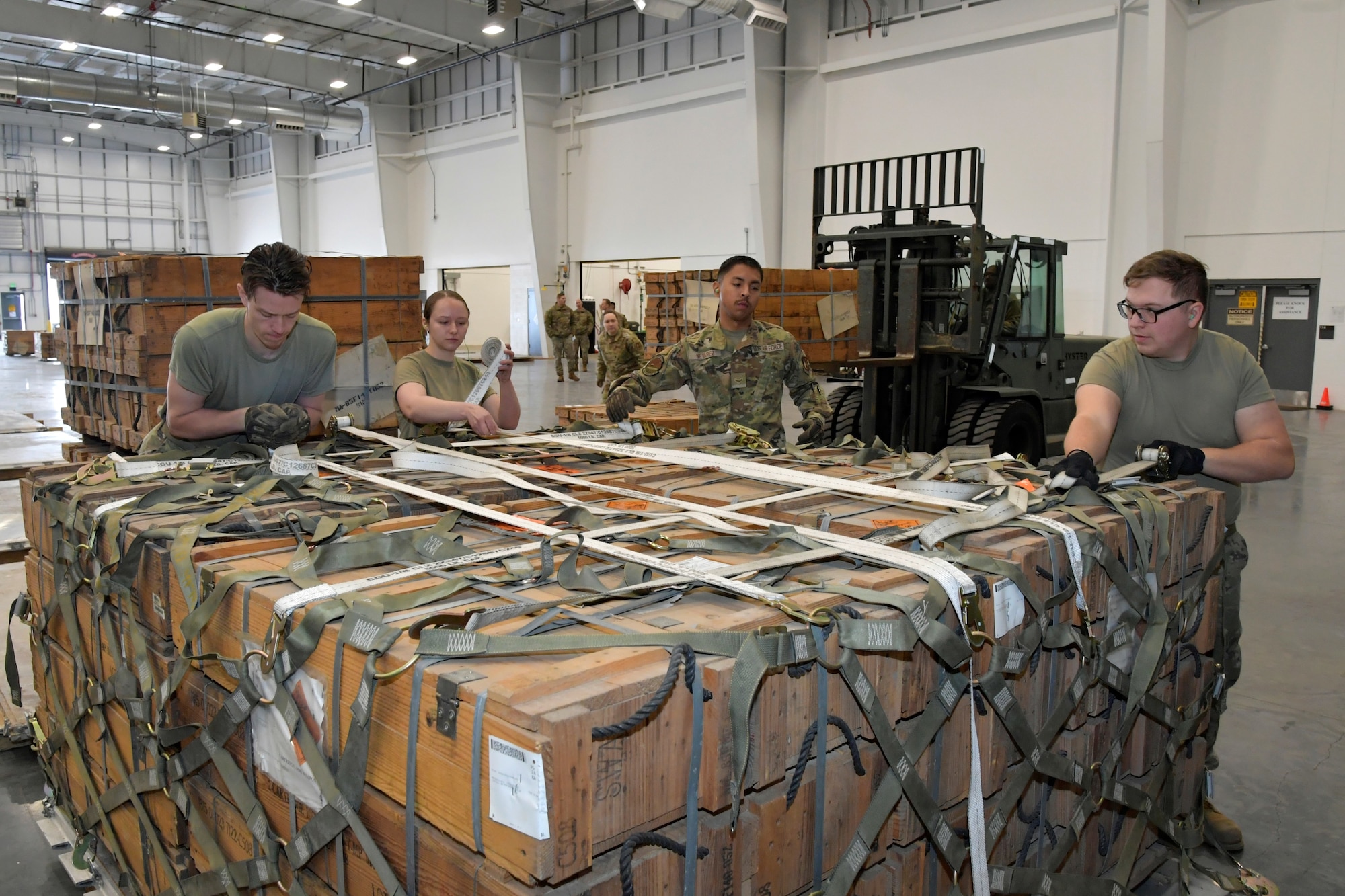 Airmen secure cargo net on pallet load