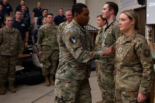  Man places patch on woman's uniform