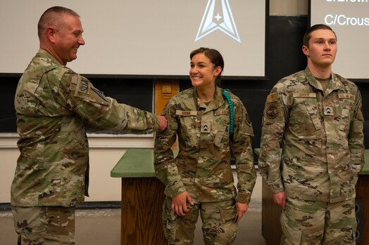  Man places patch on woman's uniform
