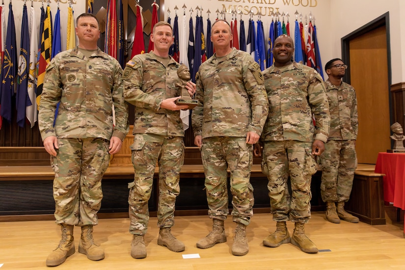 U.S. Army 1st Lt. Jason Ball (center left) received the 1st Lt. Orville Munson Award from Col. Joseph C. Goetz (right center) with Command Sgt. Major Zachary Plummer (far left) and Chief Warrant Officer 5 Dean Registe at the U.S. Army Engineer Regimental School at Fort Leonardwood, Missouri on April 28, 2023. Ball was nominated for the award by his brigade commander, U.S. Army Col. James Richmond, commander of the 149th Maneuver Enhancement Brigade, for his hardwork and dedication as a platoon leader. (U.S. Army National Guard photo by Sgt. 1st Class Andrew Dickson)