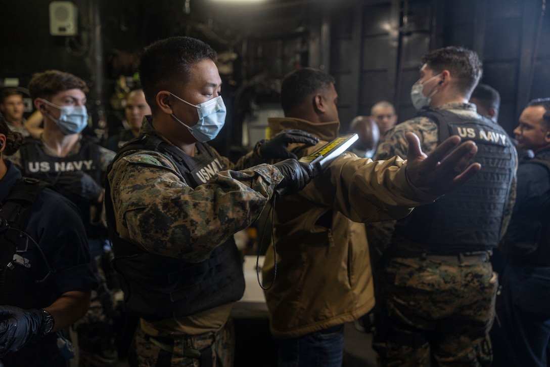 A U.S. Marine with the 26th Marine Expeditionary Unit (MEU) scans a simulated evacuee for weapons or foreign objects during a Non-combatant Evacuee Operation (NEO) part of Amphibious Ready Group/MEU Exercise (ARGMEUEX), Atlantic Ocean, April 24, 2023. The simulated evacuees were transported from a location on Camp Lejeune to the Wasp-class amphibious assault ship USS Bataan (LHD 5). The NEO was part of a training scenario exhibiting the ARG/MEU’s ability to safely transport civilians from dangerous situations and processing them for further accommodations. ARGMEUEX is the second at-sea exercise in the MEU’s Pre-deployment Training Program. (U.S. Marine Corps photo by Cpl. Matthew Romonoyske-Bean)