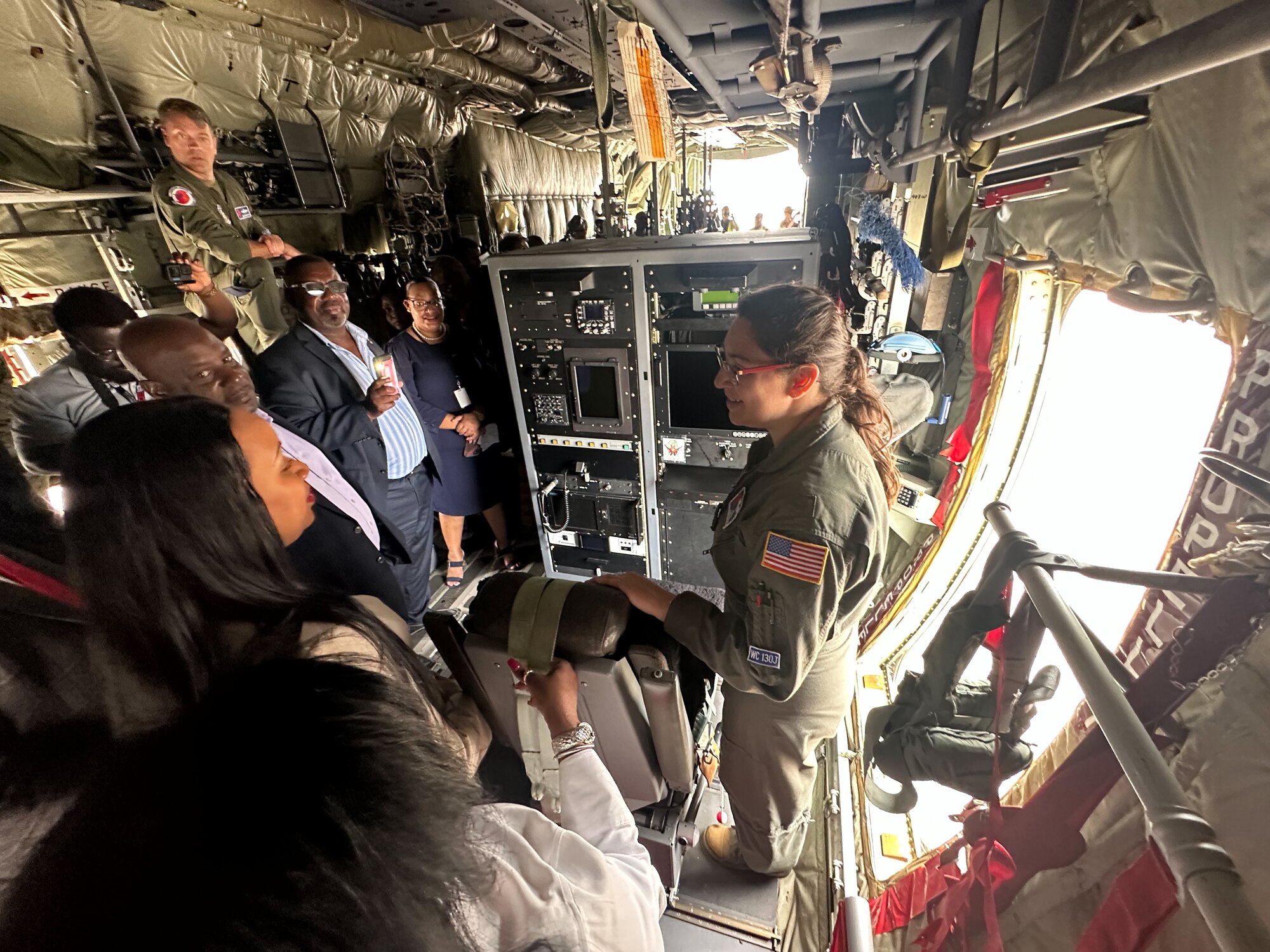 people listen as a crew member speaks inside an aircraft