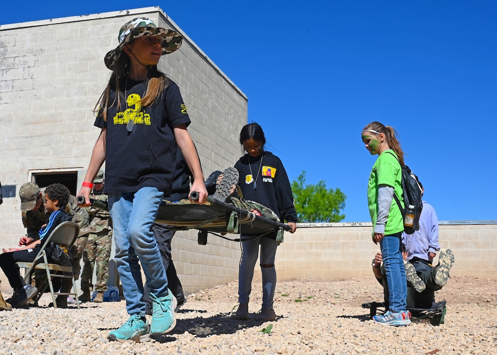Children learn how to carry a litter during Operation Kids at Goodfellow Air Force Base, Texas, April 29, 2023. Op Kids increases military children’s familiarization with the deployment process in a fun, safe, and engaging way. (U.S. Air Force photo by Airman 1st Class Zach Heimbuch)