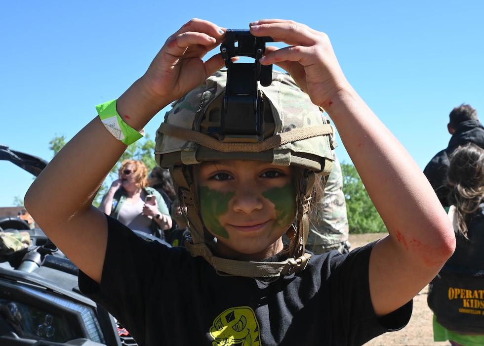 An Operation Kids participant dons a helmet at Goodfellow Air Force Base, Texas, April 29, 2023. Op Kids provided an opportunity for children in the base and local communities to familiarize themselves with activities commonly found at deployed locations. (U.S. Air Force photo by Airman 1st Class Madison Collier)