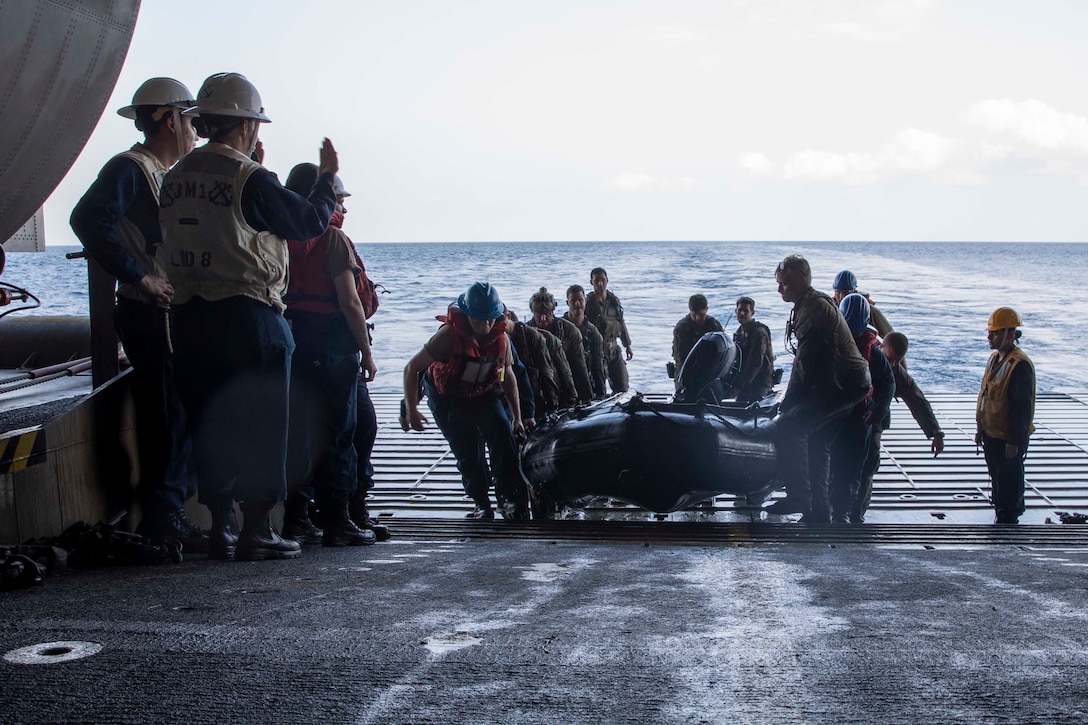 U.S. Sailors, and U.S. Marines assigned to 1st Reconnaissance, 13th Marine Expeditionary Unit carry a combat rubber raiding craft aboard amphibious assault ship USS Makin Island (LHD 8) after returning from a simulated amphibious raid for Balikatan 23, April 14, 2023 in the South China Sea. Balikatan is an annual exercise between the Armed Forces of the Philippines and U.S. military designed to strengthen bilateral interoperability, capabilities, trust, and cooperation built over decades of shared experiences. The Makin Island Amphibious Ready Group, comprised of Makin Island and amphibious transport docks USS Anchorage (LPD 23) and USS John P. Murtha (LPD 26), is operating in the U.S. 7th Fleet area of operations with the embarked 13th MEU to enhance interoperability with Allies and partners and serve as a ready-response force to defend peace and maintain stability in the Indo-Pacific region. (U.S. Navy photo by Mass Communication Specialist 2nd Class Minh-Thy Chu)