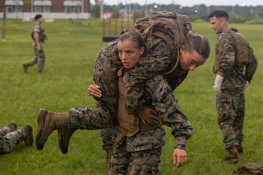 A Marine carries another Marine over her shoulder.