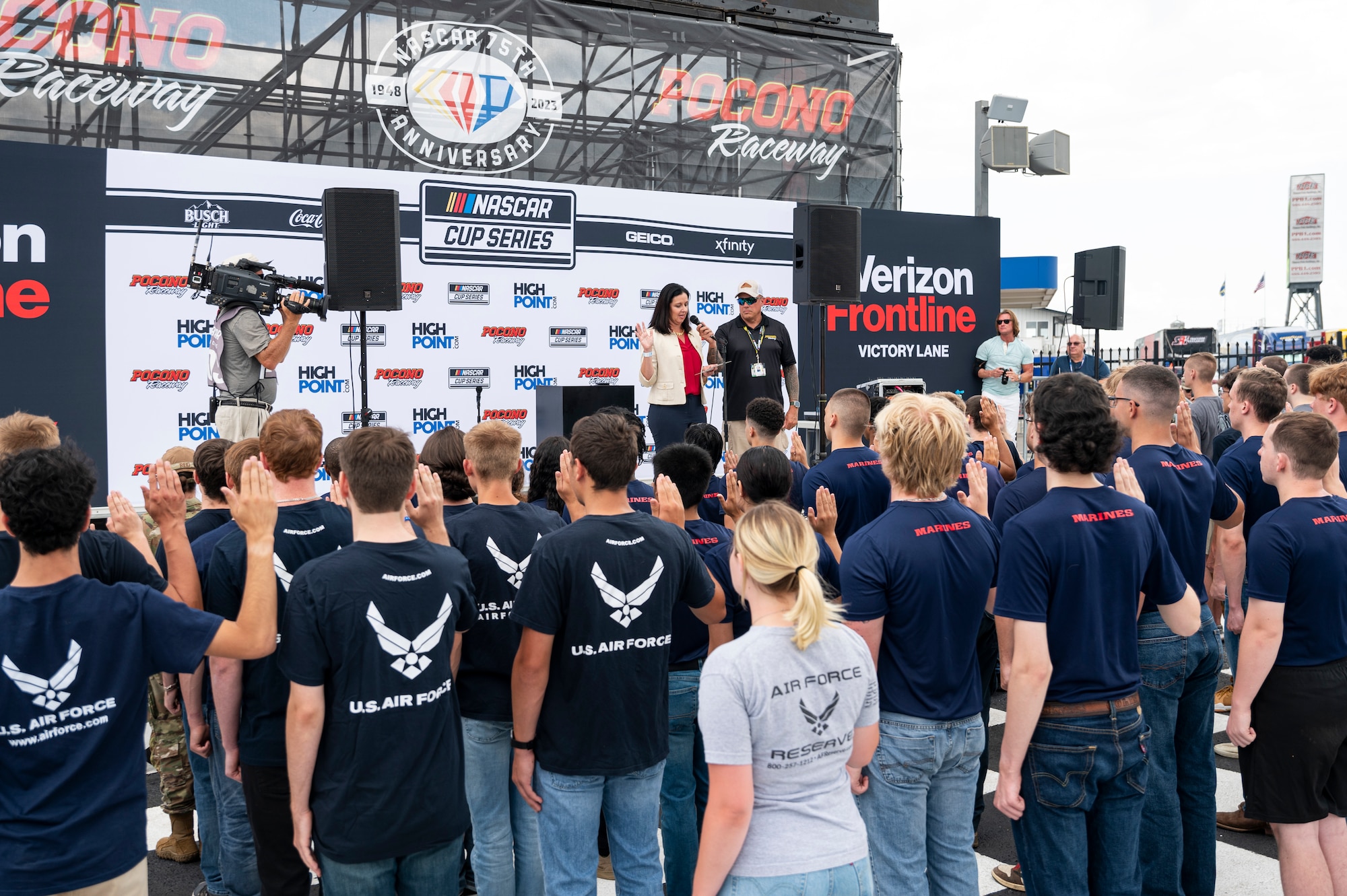 Kristyn Jones, assistant secretary of the Air Force for Financial Management and Comptroller, performing the duties of the under secretary of the Air Force, delivers the oath of enlistment to over 100 Air Force, Army, Marines and Navy recruits at Pocono Raceway, Pa., July 23, 2023. Jones visited the raceway to participate in the Air Force recruiting mission at the NASCAR Cup Series race as part of a longstanding partnership with Legacy Motor Club. (U.S. Air Force photo by Staff Sgt. Jacob B. Derry)