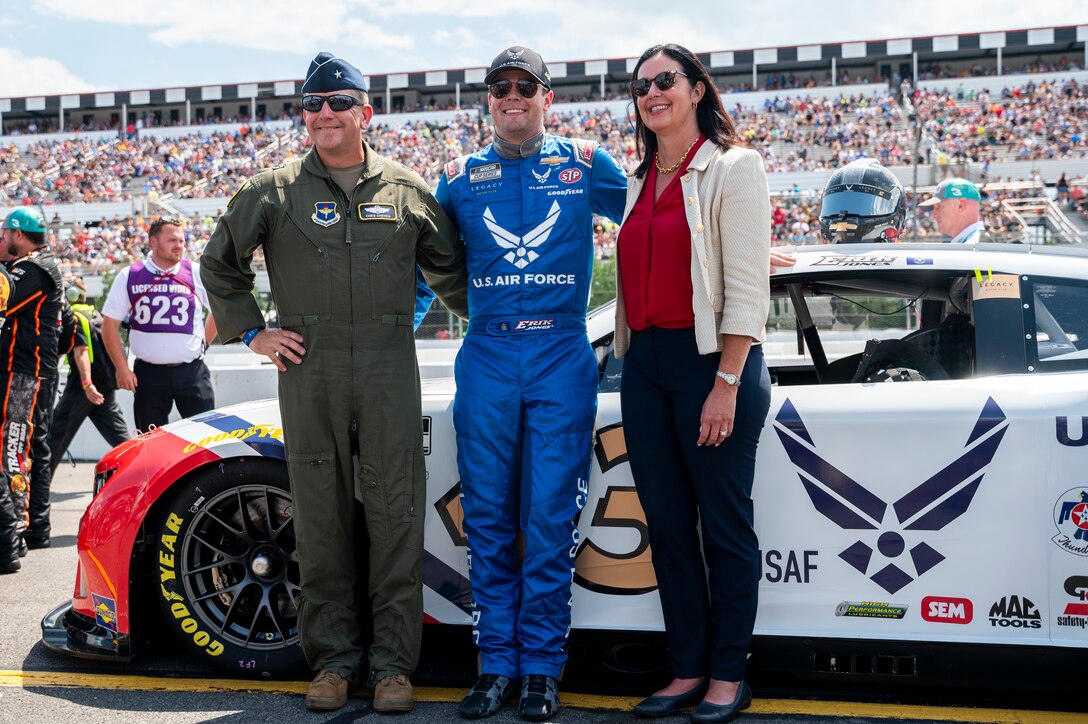 Kristyn Jones, assistant secretary of the Air Force for Financial Management and Comptroller, performing the duties of the under secretary of the Air Force, and Brig. Gen. Christopher Amrhein, Air Force Recruiting Service commander, pose for a photo with Erik Jones, a NASCAR series cup driver with Legacy Motor Club, and the Air Force themed No. 43 Camaro ZL1, at Pocono Raceway, Pa., July 23, 2023. The long-standing partnership between Legacy Motor Club and the U.S. Air Force yields at least three races during the NASCAR season in which the Air Force paint scheme is showcased on the No. 43 Chevrolet Camaro ZL1, driven by Erik Jones. (U.S. Air Force photo by Staff Sgt. Jacob B. Derry)