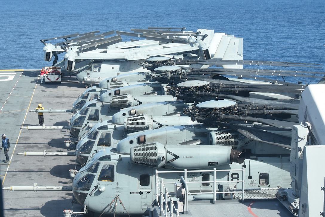 Helicopters sit in a row on a vessel.