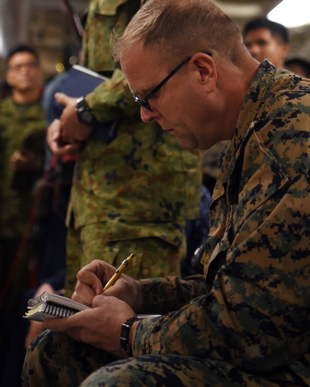 A uniformed service member writes in a notebook.