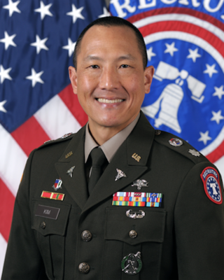 Male Soldier posed in front of the U.S. flag and the USAREC flag.