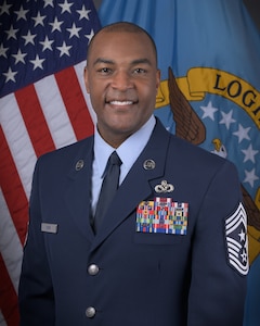 A portrait of Command Chief Master Sergeant Alvin R. Dyer in an Air Force uniform in front of an American flag and Defense Logistics Agency flag