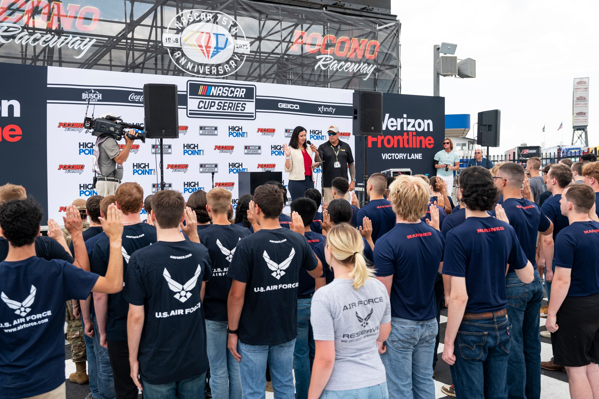 Kristyn Jones, assistant secretary of the Air Force for Financial Management and Comptroller, performing the duties of the under secretary of the Air Force, delivers the oath of enlistment to over 100 Air Force, Army, Marines and Navy recruits at Pocono Raceway, Pa., July 23, 2023. Jones visited the raceway to participate in the Air Force recruiting mission at the NASCAR Cup Series race as part of a longstanding partnership with Legacy Motor Club. (U.S. Air Force photo by Staff Sgt. Jacob B. Derry)