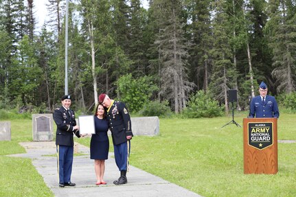 Command Sgt. Maj. Michael Grunst hugs his wife, Charity, as she is presented with an award from Maj. Patrick Gargan for her strength and contributions supporting her husband throughout his career during Grunst’s retirement ceremony July 21, 2023, at Camp Carroll on Joint Base Elmendorf-Richardson.