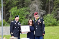 Maj. Patrick Gargan, left, presents Charity with an award for her strength and contributions supporting her husband, Command Sgt. Maj. Michael Grunst, right, throughout his career during his retirement ceremony July 21, 2023, at Camp Carroll on Joint Base Elmendorf-Richardson.