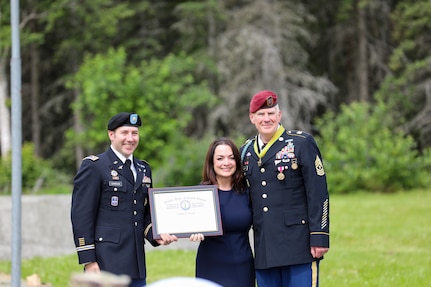 Maj. Patrick Gargan, left, presents Charity with an award for her strength and contributions supporting her husband, Command Sgt. Maj. Michael Grunst, right, throughout his career during his retirement ceremony July 21, 2023, at Camp Carroll on Joint Base Elmendorf-Richardson.
